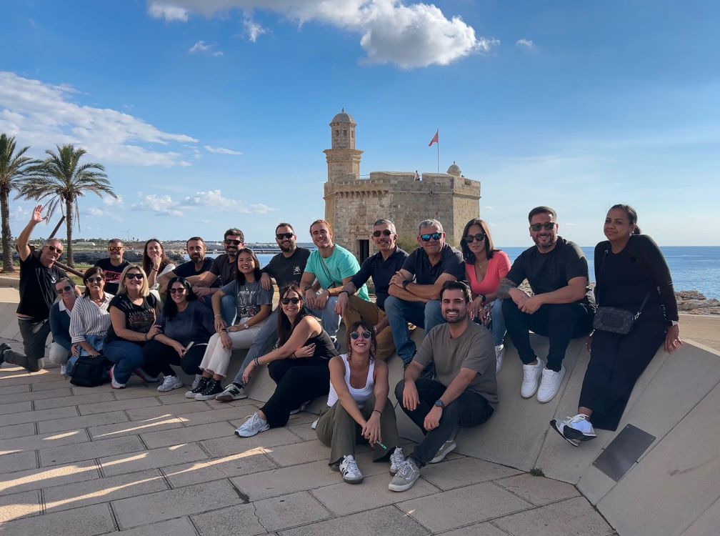 Equipo directivo y responsables de Divertha en jornada de team building en Menorca. Foto de grupo sonriente, clave para la cohesión y el liderazgo de la empresa de servicios en Mallorca